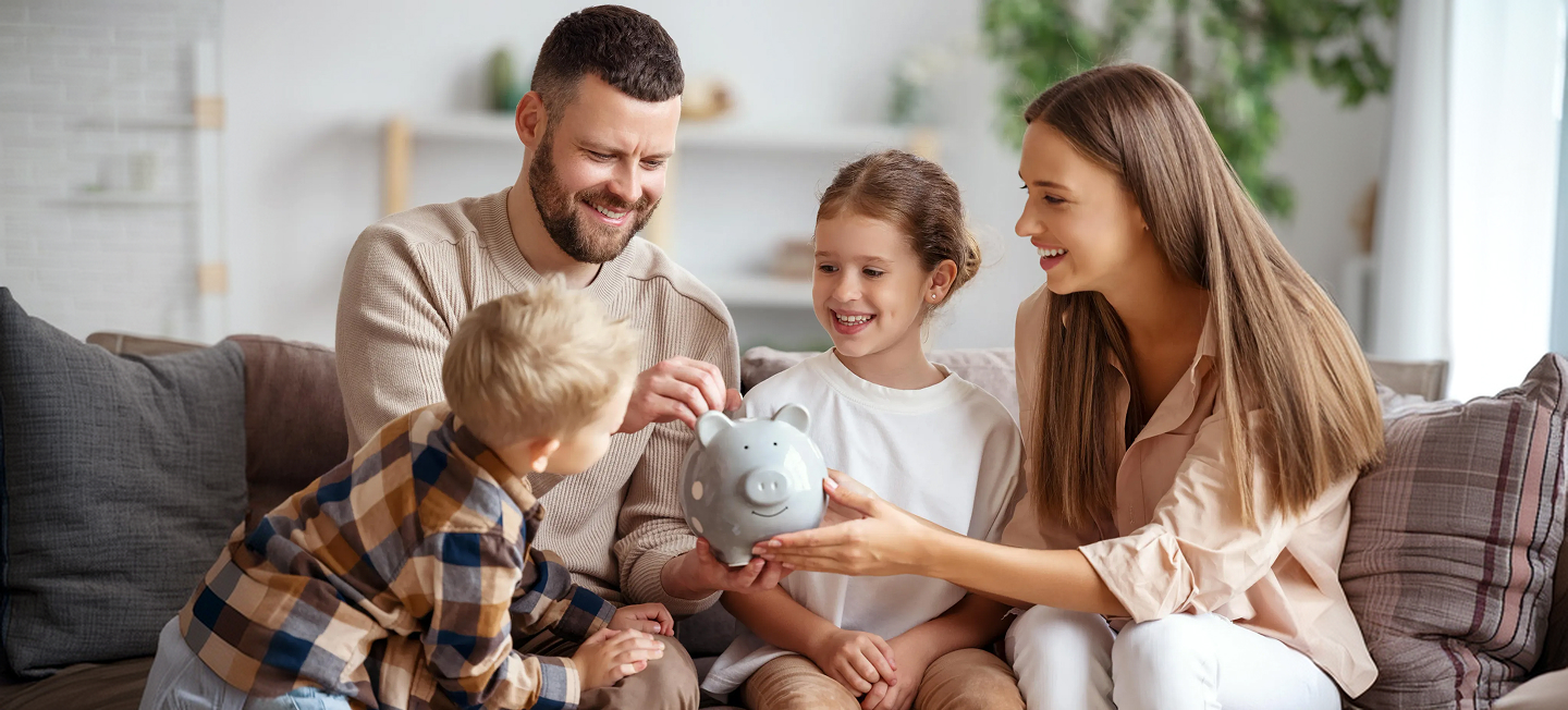 precio luz hoy: Familia joven metiendo dinero en una hucha